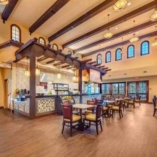A spacious restaurant interior featuring wooden beams, elegant lighting, and an inviting dining area.