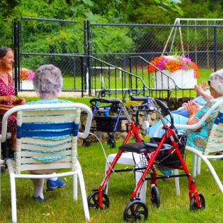 A group of elderly people enjoying a social gathering outdoors in a garden.
