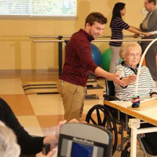 A physical therapist assists an elderly patient during a rehabilitation session in a care facility.