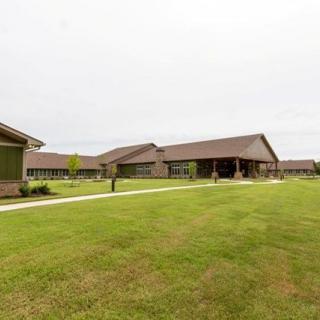 A view of a modern building complex with a large lawn and an overcast sky.