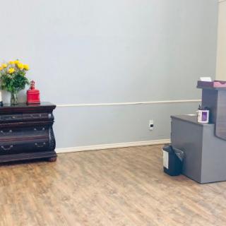 A simple reception area with a desk and flowers on display.