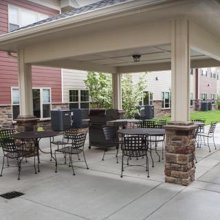 Outdoor patio area with seating and a grill under a pergola.