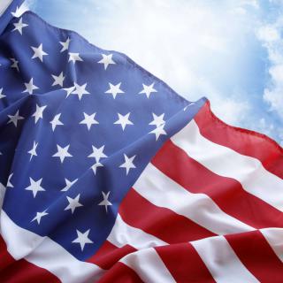 An American flag waving against a blue sky.