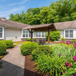 A charming house with a well-maintained garden and patio area surrounded by lush greenery.