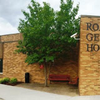 Exterior view of a brick hospital building with a tree and bench.