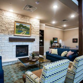 A cozy living room featuring a stone fireplace, comfortable seating, and tasteful artwork.