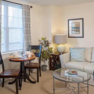 A cozy living room with a sofa, coffee table, and a dining area by the window.