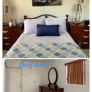 A cozy bedroom with a neatly made bed, featuring bedside tables and a mirror.