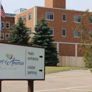 A view of a healthcare facility with directional signage for visitors and parking.