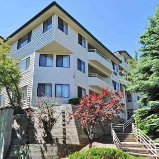 A modern apartment building with well-maintained landscaping and clear blue sky.