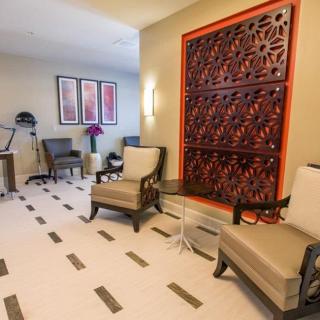 A well-decorated waiting room featuring comfortable chairs, a table, and intricate wall art.