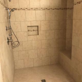 A tiled walk-in shower with a built-in bench and wall niche.