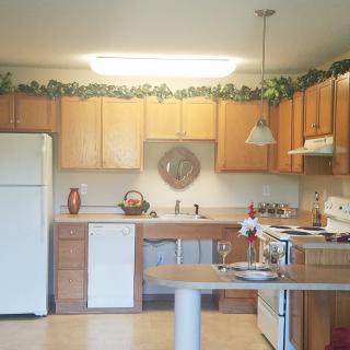 A cozy kitchen with wooden cabinets, a white refrigerator, and an island.