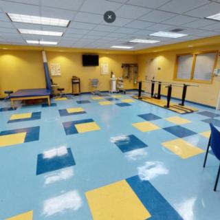 A brightly colored physical therapy room equipped with various rehabilitation equipment.