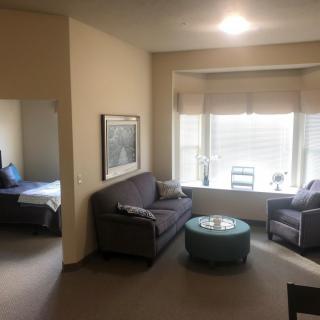 A cozy living room with a sofa, armchair, and coffee table near a large window.