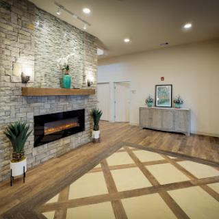 A modern living room featuring a stone wall fireplace, stylish decor, and elegant flooring.