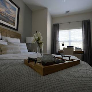 A cozy and elegantly styled bedroom featuring a comfortable bed, soft bedding, and a decorative tray with flowers.