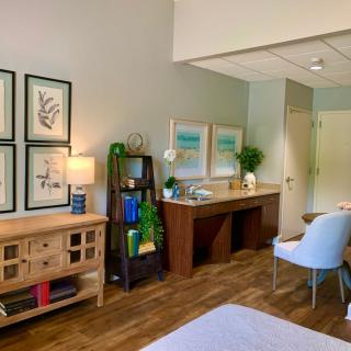 A cozy and well-decorated room with wooden furniture, artwork on the walls, and green plants for a touch of nature.