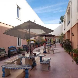 A spacious outdoor patio with multiple seating areas and a large umbrella under a clear blue sky.