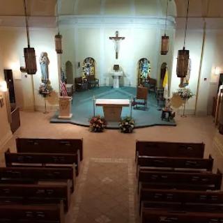 Interior view of a church with an altar and rows of pews.