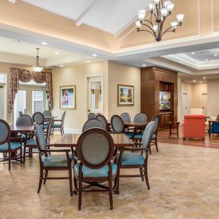 Elegant dining area with tables and chairs arranged in a spacious interior, featuring tasteful decor and warm lighting.