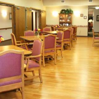 An empty dining room with wooden tables and chairs on a hardwood floor.