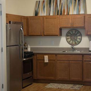 A modern kitchen with wooden cabinets, stainless steel appliances, and decorative artwork.