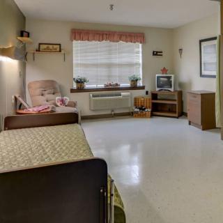 A clean and tidy hospital room with a bed, chair, and television.