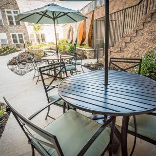 A cozy outdoor patio area featuring tables with umbrellas and chairs, set in a well-maintained garden.