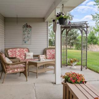 A cozy patio area with wicker chairs and floral cushions, overlooking a lush garden.
