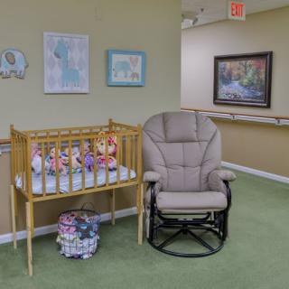 A cozy nursery corner featuring a crib with colorful toys, a comfortable rocking chair, and charming wall art.