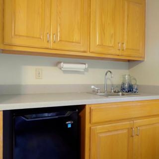A small kitchen area featuring wooden cabinets, a countertop with a sink, and a mini fridge.