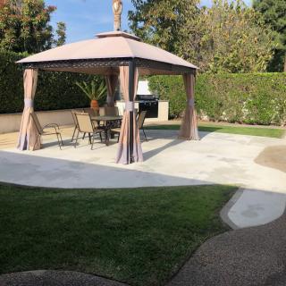A sunny backyard patio with a gazebo and outdoor furniture.