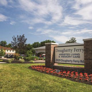 Entrance to a facility with a landscaped garden and sign.