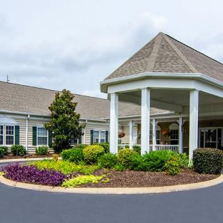 A welcoming building entrance with well-maintained landscaping and a circular driveway.