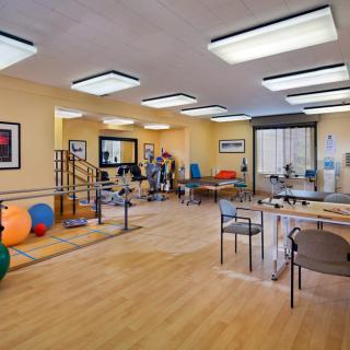 A well-equipped physical therapy room featuring various exercise equipment and a spacious layout for rehabilitation activities.