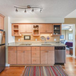 A modern kitchen with wood cabinets, stainless steel appliances, and a striped rug in an open layout.