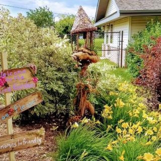 A vibrant garden scene with blooming flowers, a decorative signpost, and a house in the background.