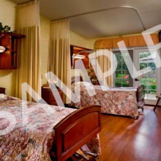 A cozy bedroom with two beds, floral bedspreads, and a large window providing natural light.