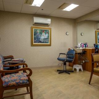 A cozy hair salon waiting area with chairs, mirrors, and a painting on the wall.