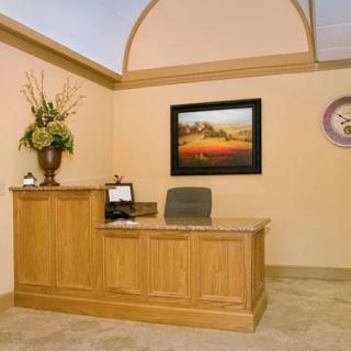 Front desk area with a wooden reception counter, wall art, and a clock.