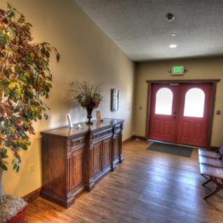 A warm and inviting hallway leading to double doors, featuring a decorative plant and wooden furniture.
