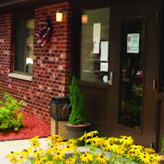A welcoming entrance adorned with vibrant yellow flowers and a brick facade.