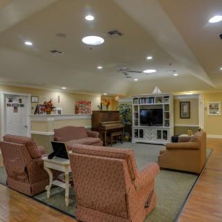 A cozy living room featuring comfortable seating, a piano, and a TV.
