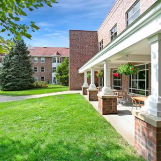 A peaceful view of a well-maintained building with green grass and trees under a clear blue sky.