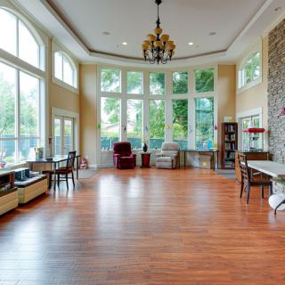 A spacious living room with large windows, hardwood flooring, and elegant furnishings.