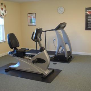 A small gym with a treadmill and a stationary bike.
