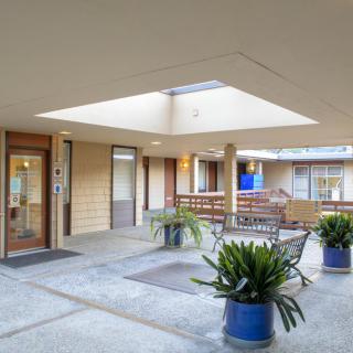 A modern indoor courtyard featuring a skylight, plants, and seating areas.