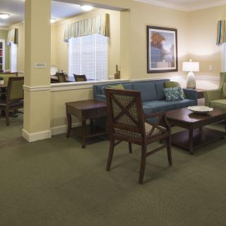 A well-furnished living room with sofas, chairs, and a coffee table on a carpeted floor.