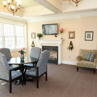 A cozy living area featuring a dining table, comfortable seating, and a fireplace, illuminated by natural light.